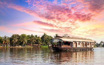 House boat in backwaters near palms at dramatic sunset sky in alappuzha, Kerala, India